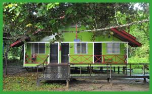 a green and red house with a porch in front of it at Sukau Greenview Bed & Breakfast in Sukau