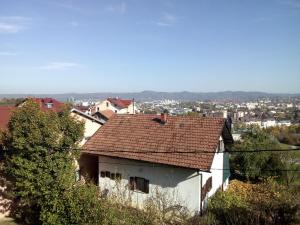 巴尼亞盧卡的住宿－Apartmani "Babići"，一座白色的房子,有红色的屋顶,城市