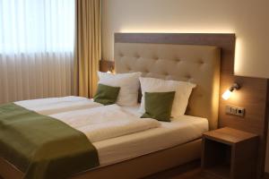 Un dormitorio con una cama grande con almohadas verdes y blancas en Landhaus Jägerkrug en Paderborn