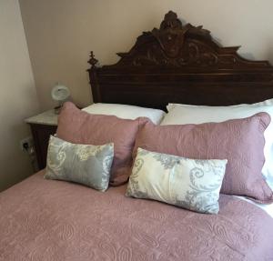 Una cama con almohadas rosas y blancas. en Eight ball house, en Southburgh