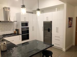 a kitchen with white cabinets and a stainless steel refrigerator at Warm on Waterloo in Palmerston North
