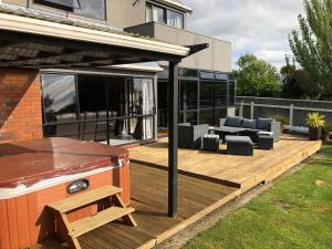 a deck with a grill and furniture on a house at Warm on Waterloo in Palmerston North