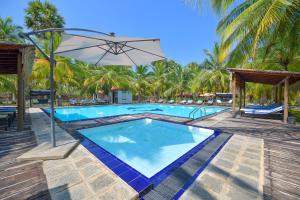 uma piscina com guarda-sol e palmeiras em De Silva Palm Resort em Kalpitiya