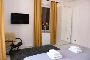 ローマにあるRampa Brancaleone Apartmentのベッド、テレビ、椅子が備わる客室です。