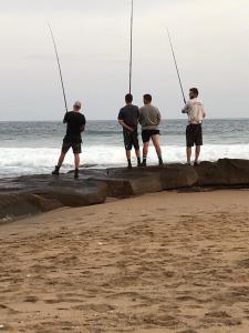 a group of men standing on the beach holding fishing rods at IRONWOOD LODGE in Pennington