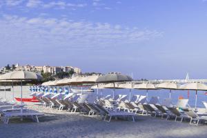 eine Gruppe von Stühlen und Sonnenschirmen am Strand in der Unterkunft Hotel Tirreno in Parghelia