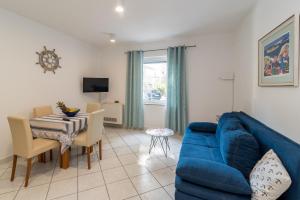 a living room with a blue couch and a table at Apartments Irena Krk in Krk