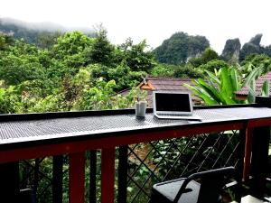 a laptop computer sitting on a table on a balcony at Khao Sok Morning Mist Resort in Khao Sok National Park