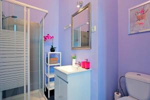 een paarse badkamer met een wastafel en een spiegel bij Localtraveling ALFAMA River View - Family Apartments in Lissabon