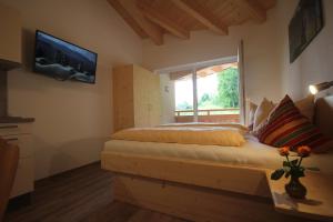 a bedroom with a bed and a television on the wall at Ferienwohnungen Karwendel Camping in Maurach