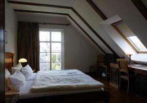 a bedroom with a bed and a window and a desk at Hotel Snorrenburg GmbH in Burbach