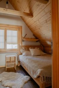a bed in a room with a wooden ceiling at Biolo i Corno Izba Mountain Chalets in Kościelisko