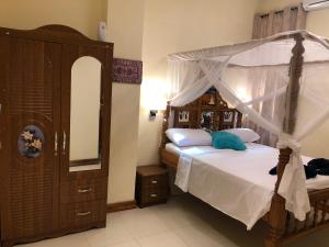 a bedroom with a canopy bed and a dresser at Bottoms Up in Zanzibar City