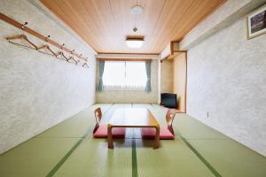 a room with a table and chairs and a television at Hotel Station Kyoto West in Kyoto