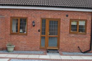 un edificio de ladrillo con puertas y ventanas de madera en Oldcotes Cottages, en Firbeck