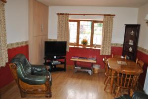 sala de estar con TV, mesa y sillas en Oldcotes Cottages, en Firbeck