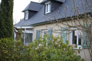 una casa con ventanas azules y techo negro en Chambres Le Mans 24 heures, en Arnage