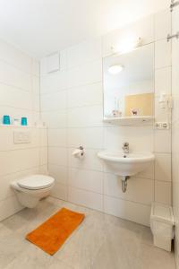 a white bathroom with a toilet and a sink at Pension Weinbauer in Hofkirchen im Traunkreis