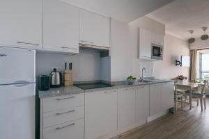 a white kitchen with white cabinets and a table at BINIS Apartment in Funchal