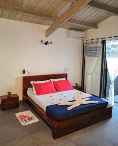 1 dormitorio con 1 cama grande con almohadas rojas en Les 3 Soleils, en Saint-Joseph