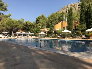 a large swimming pool with tables and umbrellas at Camping La Puerta in Moratalla