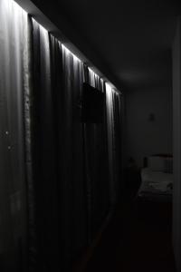 a dark room with a window with curtains and a television at Hotel Magurele in Măgurele