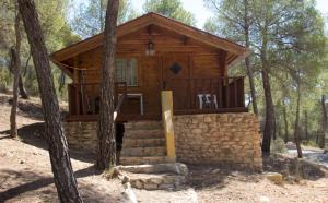 una cabaña de madera en el bosque con 2 sillas en Camping La Puerta, en Moratalla