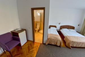 a room with two beds and a chair and a mirror at Pension Alexia in Sibiu