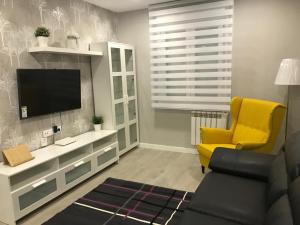 a living room with a tv and a yellow chair at Apartamento Expectacular,céntrico,nuevo 5 min a pie de la Laurel Vivienda de uso Turistico in Logroño