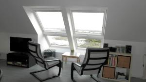 twee stoelen in een woonkamer met twee ramen bij Location Tromeal Lasalle in Saint-Pol-de-Léon