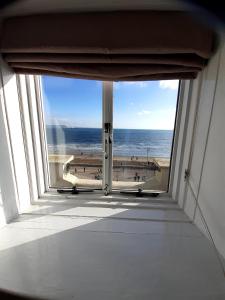 a room with a view of the beach from a window at The Edenhurst Guesthouse in Weymouth