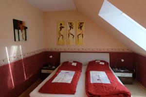 2 camas en un ático con sábanas rojas en Afrikanisches Ambiente, en Salzhemmendorf