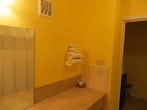 a bathroom with yellow walls and a shower with towels at Cottonwood Inn in La Grange