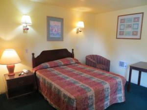 Habitación de hotel con cama, mesa y lámpara en Cottonwood Inn, en La Grange