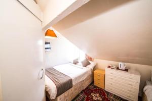 a small attic bedroom with a bed and a dresser at MyRoomz Hollingdales Hotel in Blackpool