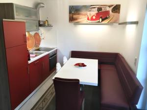 a small kitchen with a white table and red cabinets at Ferienhaus Feel like Home Barbecue in Hamburg