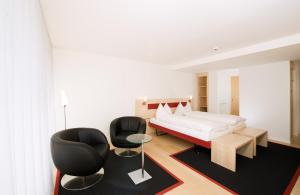 ein Schlafzimmer mit einem Bett und zwei schwarzen Stühlen in der Unterkunft Hotel Seaside in Spiez