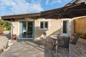 a patio with a table and chairs and an umbrella at Domaine Jean-Got, proche de Saint Emilion in Lugaignac