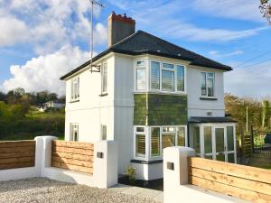 a white house with a wooden fence in front of it at The Cornish Retreat in Bude
