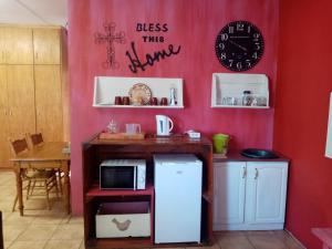 kuchnia z lodówką i zegarem na ścianie w obiekcie Oornagkamers@Hillstraat10 w mieście Douglas