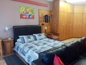ein Schlafzimmer mit einem Bett und einem Ledersofa in der Unterkunft Oornagkamers@Hillstraat10 in Douglas