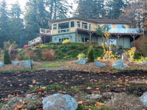 a house on a hill with rocks in front of it at Sunrise Suite on the Sound in Anacortes