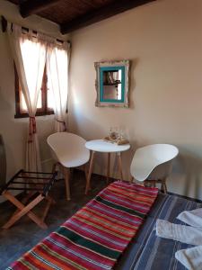 Habitación con mesa, 2 sillas y alfombra. en Hostal Asqui Pacha en Tilcara