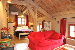 a living room with a red couch and a bed at B&B Le Clos de la Fontaine in Chéoux