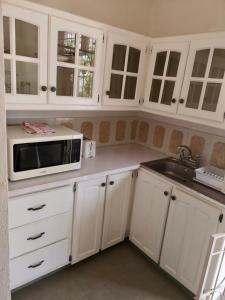 a white kitchen with a microwave and a sink at Ventnor House Apartments in Bridgetown