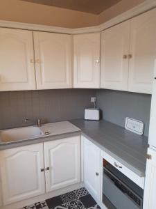 a kitchen with white cabinets and a sink and a counter at Iliade in Rue