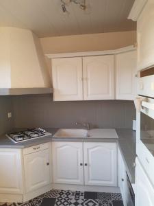 a kitchen with white cabinets and a sink and a stove at Iliade in Rue