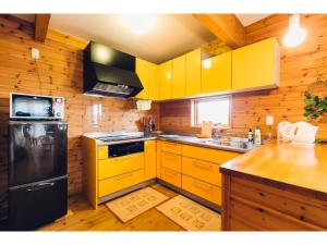 cocina con armarios amarillos y nevera negra en LAKE view PRIVATE log house, en Lago Toya