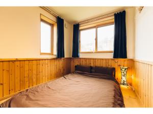 a large bed in a room with two windows at LAKE view PRIVATE log house in Lake Toya