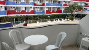 un balcón con sillas y una mesa y un edificio en Apartamento de 1 quarto de frente a praia dos Ingleses, en Florianópolis
